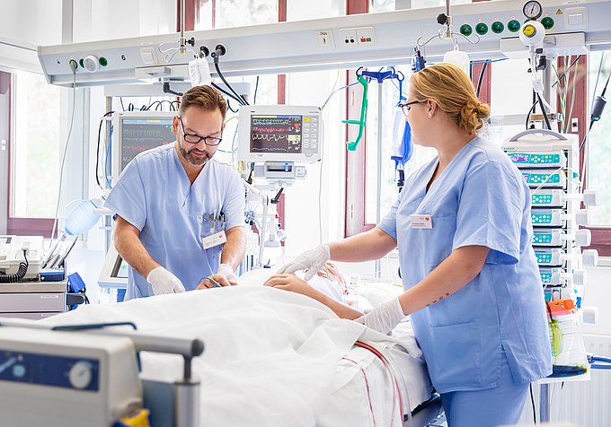 Dies sind zwei Pflegekräfte der Intensivstation, die einen Patienten nach seiner Operation versorgen.