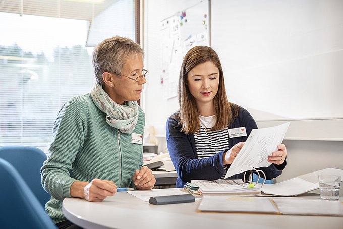 Dies sind zwei Mitarbeiterinnen des Qualitätsmanagements bei einer Besprechung im Büro.