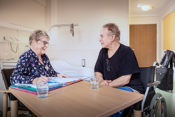 Dies zeigt eine Mitarbeiterin des Entlassmanagements im Gespräch mit einem Patienten.