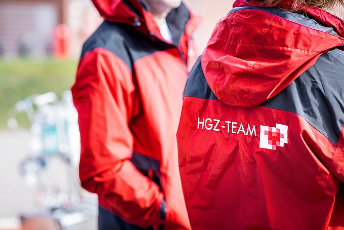 Dies ist eine Nahaufnahme der Einsatzjacke von zwei Mitarbeitern des HGZs mit dem Aufdruck "HGZ-Team".