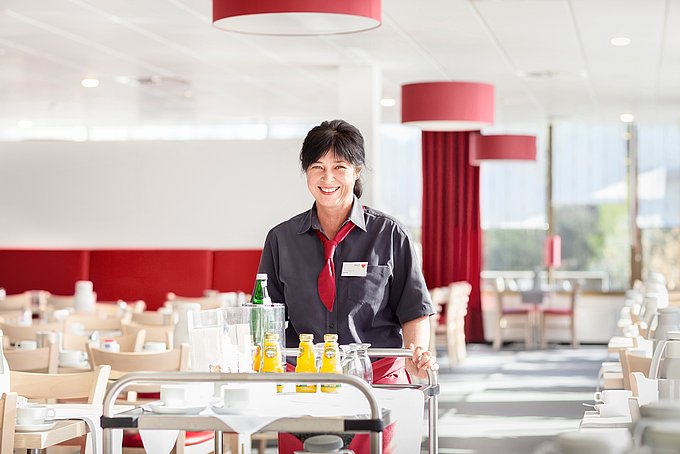 Dies ist eine lächelnde Servicekraft in der hellen Cafetria.