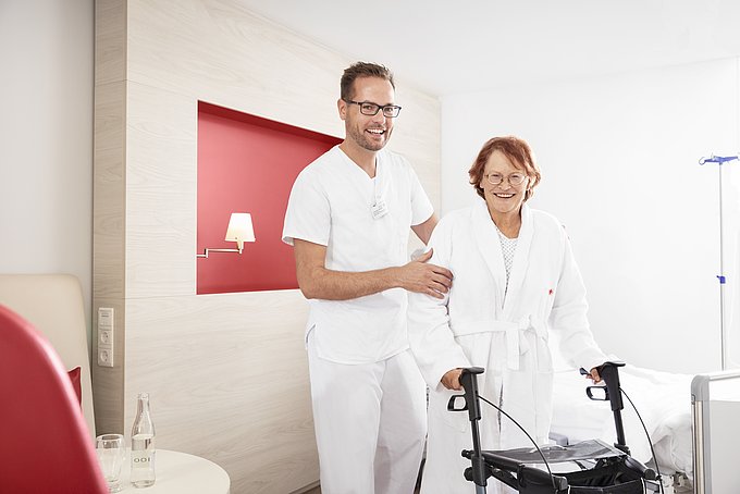 Dies ist ein Pfleger, der einer älteren Patientin hilft.