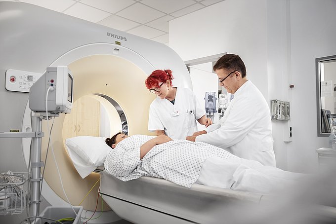 Dies sind ein Radiologe und eine MTRA, die eine Patientin auf eine Kardio-CT-Untersuchung vorbereiten.